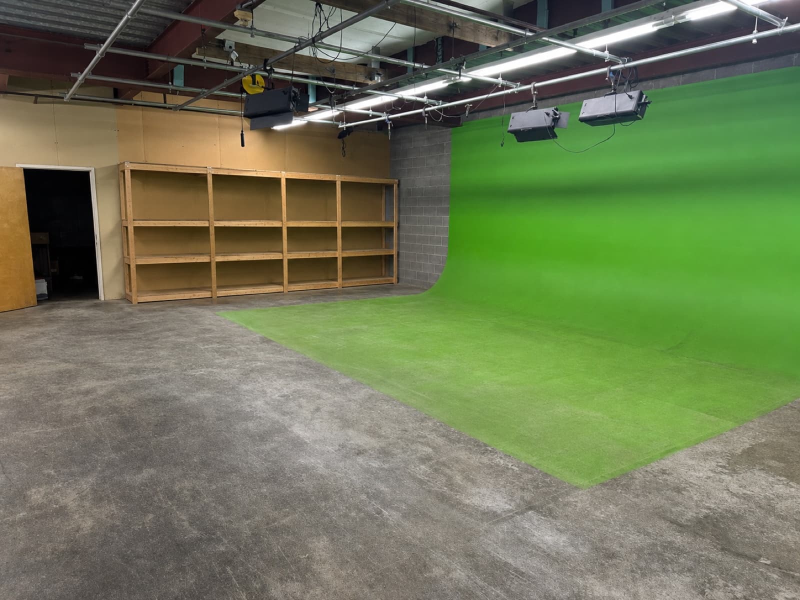 Existing green-screen wall and overhead light cages — stay with the space if useful